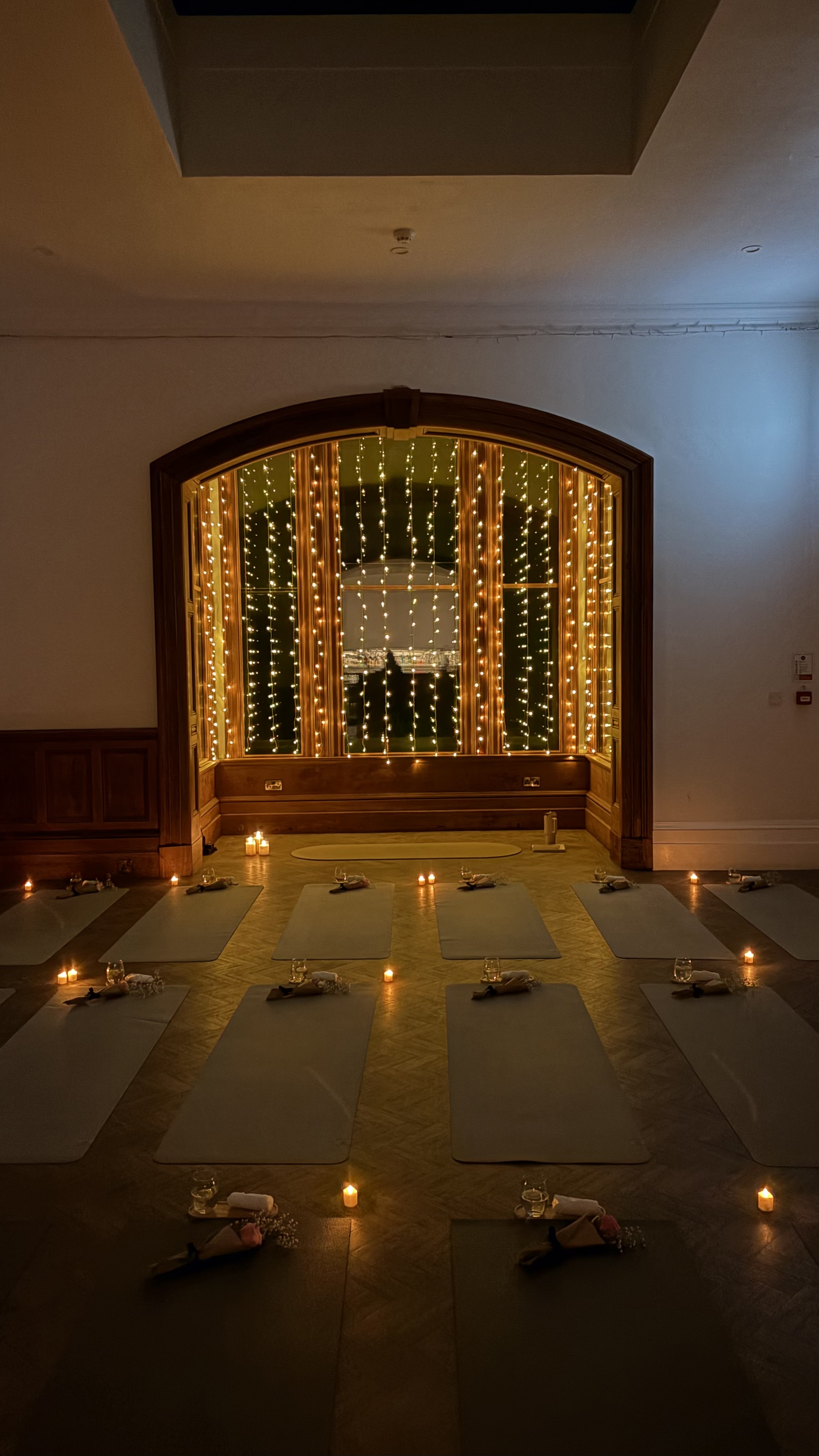 Pilates equipment laid out in candle and fairy-light lit room